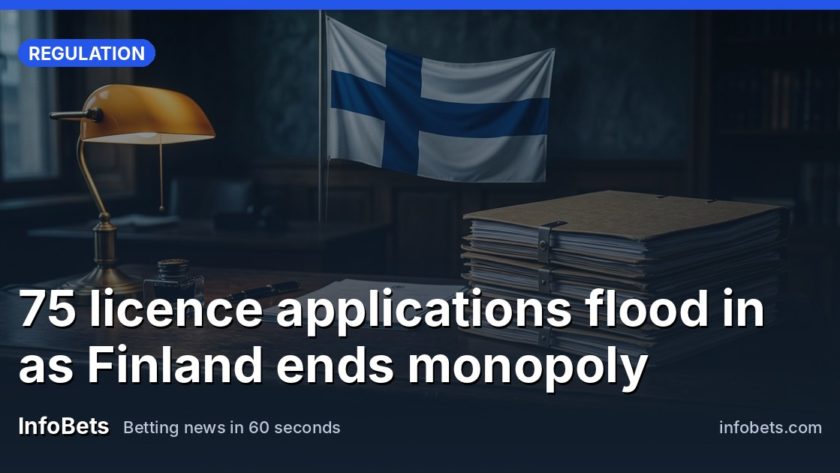 A stack of licence application folders on a government office desk beneath a Finnish flag.