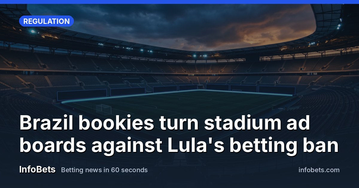 An empty football stadium at dusk with blank advertising boards ringing the pitch.