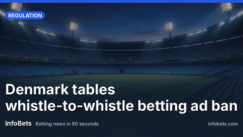 An empty outdoor sports stadium at dusk with floodlights on & no advertising boards visible.
